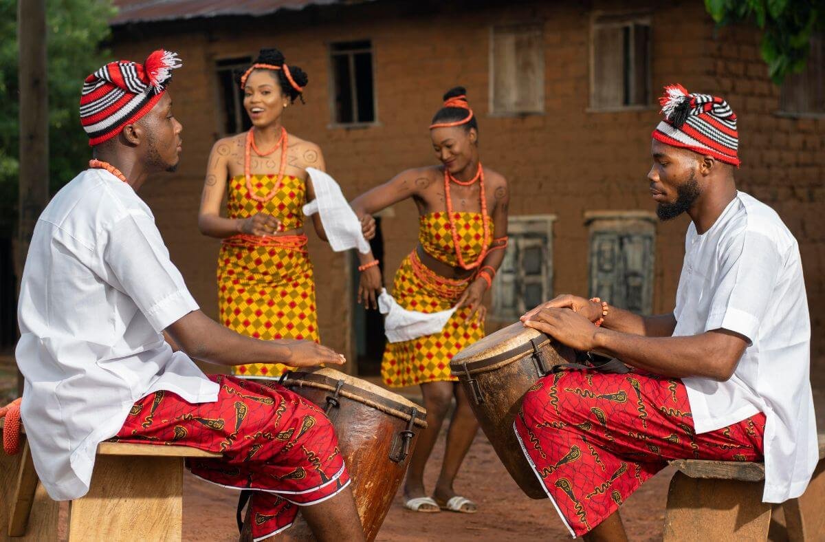 Two Igbo men and women playing drums and dancing