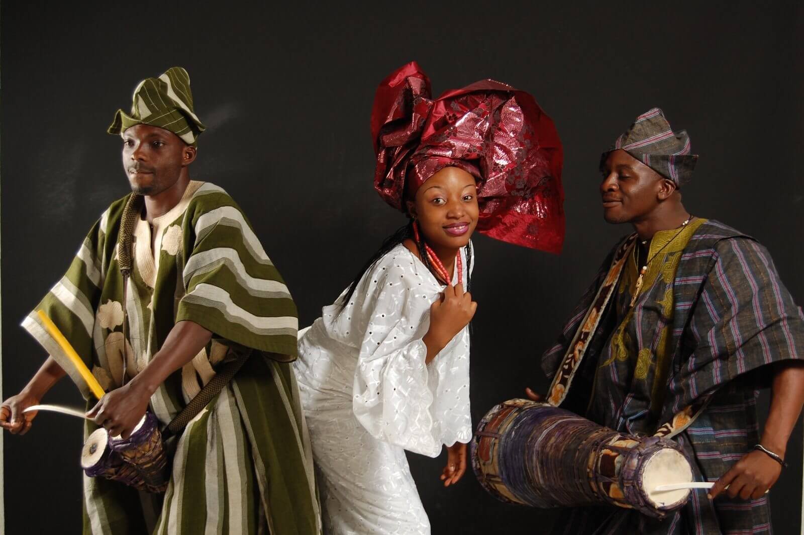 Two Yoruba men and a Yoruba woman dancing to the talking drum